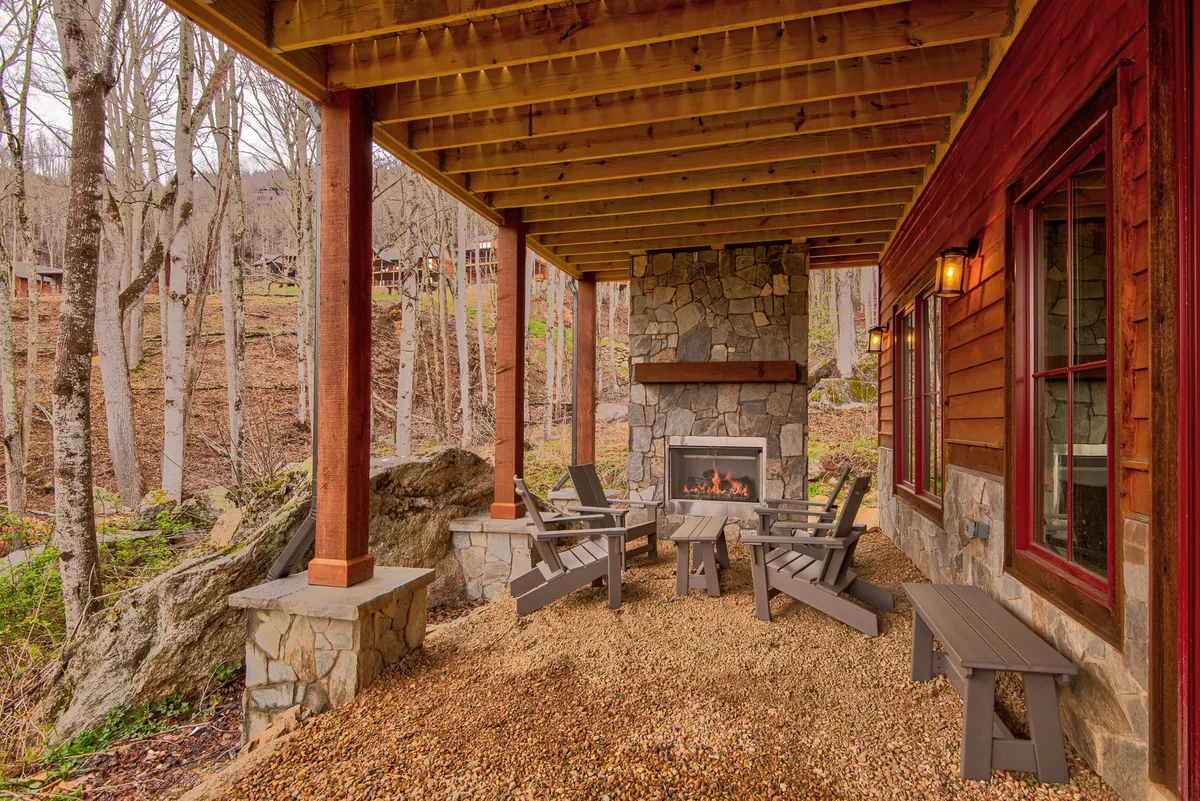 A cozy outdoor living space featuring a stone fireplace, wooden beams, and comfortable seating, all set against natural surroundings. The space invites relaxation after an active day in the mountains.